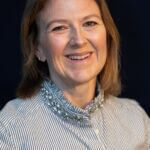 Meghan is wearing a striped buttoned shirt with jewels around the collar.