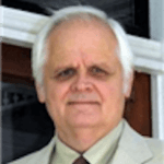 Walter has gray hair and is wearing a tan suit and tie